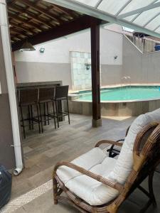 Habitación con silla y piscina en Casa de praia, en Guarujá