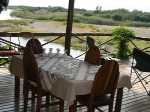 a table on a deck with a view of a river at River Bank Lapa in Upington