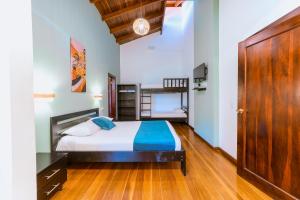 1 dormitorio con 1 cama y suelo de madera en Terrazas del Caribe Aparthotel, en Puerto Viejo