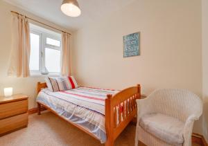 a bedroom with a bed and a chair and a window at Hallstatt in Saundersfoot