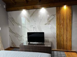 a bedroom with a television on a wall with a marble wall at Moradas Desterro, próximo ao aeroporto 24 in Florianópolis