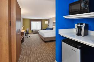 a small hotel room with a bed and a kitchen at Holiday Inn Express & Suites Chesapeake, an IHG Hotel in Chesapeake