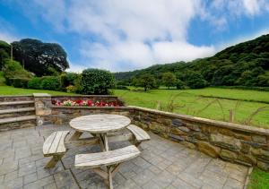 a wooden table and two benches sitting next to a stone wall at Llysyfelin in Pontfaen