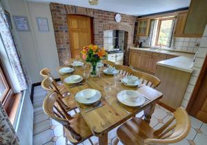 a kitchen with a wooden table with chairs and flowers at Llysyfelin in Pontfaen