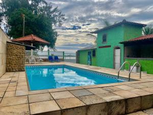 a swimming pool in front of a green building at Casa Lagoa Piscina in Araruama