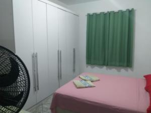 a room with a pink bed and a green curtain at Casa Lagoa Piscina in Araruama