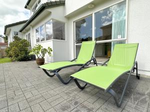 dwa krzesła siedzące na patio przed domem w obiekcie Cheerful 4 bedrooms home with stunning sunshine w Auckland