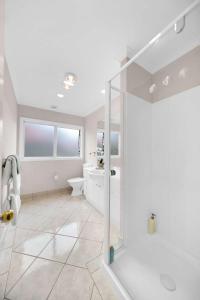 biała łazienka z prysznicem i umywalką w obiekcie Cheerful 4 bedrooms home with stunning sunshine w Auckland