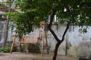 une chaise en bois assise à côté d'un arbre dans l'établissement No. 6 Cuobian Hostel, à Shantou