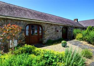 a stone house with a wooden door in a garden at Holly Cottage in Haverfordwest