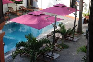 a pink umbrella and chairs next to a swimming pool at Villa Mahasok hotel in Luang Prabang