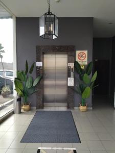 a lobby with a silver door and two potted plants at Sp Central Hotel in Sungai Petani