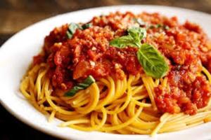 a plate of spaghetti with meat sauce and basil at Golden Ganesha Hotel Yogyakarta by Ecommerceloka in Gondowulung