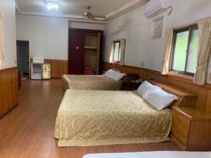 two beds in a room with wooden floors at Xiaoye Liu Homestay in Guoxing