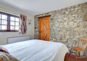 1 dormitorio con cama y pared de piedra en Vine, en Walton West