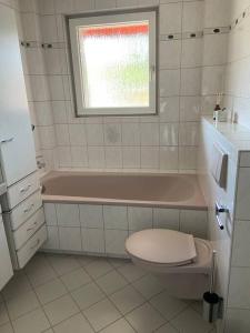 een badkamer met een roze bad, een toilet en een raam bij SCHÖNE HELLE FERIENWOHNUNG in Wehr