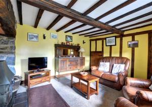 a living room with leather furniture and a flat screen tv at Gors in Llanfair Caereinion