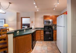 a kitchen with wooden cabinets and a white refrigerator at Comfortable Zephyr Mountain Lodge condo with the perfect view from the balcony condo in Winter Park