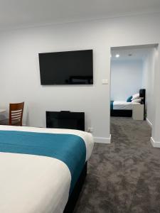 a hotel room with a bed and a flat screen tv at Beach Hotel in Burnie