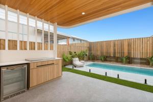 a backyard with a swimming pool and a house at Beach Life Luxury Escape Kingscliff in Kingscliff