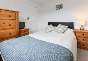 a bedroom with a blue and white bed and a dresser at Tyddyn Talgoch Isaf in Abersoch