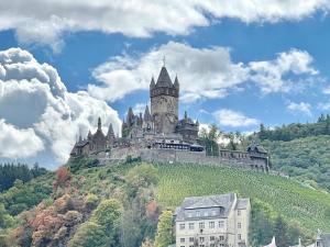 a castle on top of a hill with buildings at FeWo.Mosel.barrierefrei+modern in Treis-Karden