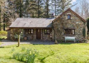 a stone house in a field of green grass at Ty Rowan in Trefriw