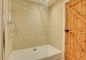a bathroom with a shower with a tub and a shower door at Ty Rowan in Trefriw
