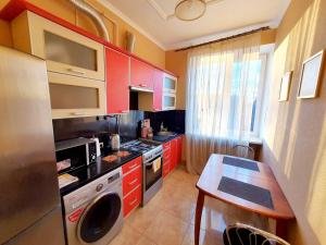 eine Küche mit roten Schränken und einem Tisch darin in der Unterkunft Двокімнатні апартаменти у центрі in Luzk