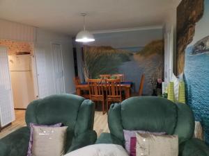a living room with two green chairs and a table at The DOLPHIN PLACE in Australind