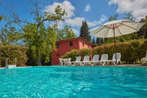 a swimming pool with chairs and an umbrella at Tenuta di Ghizzano Resort in Ghizzano