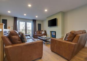 a living room with leather furniture and a flat screen tv at The Retreat in Saundersfoot