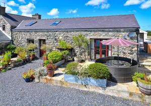 a garden in front of a stone house with an umbrella at The Barn in Llannor