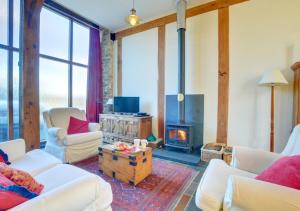 a living room with white furniture and a fireplace at Threshing Barn in Llansawel