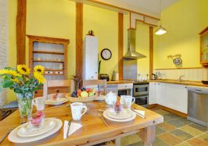 a kitchen with a wooden table with plates and flowers at Pipistrelle in Llansawel