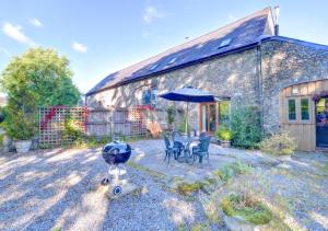 a stone house with a table and chairs and an umbrella at Pipistrelle in Llansawel