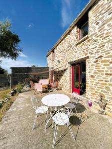 un patio con tavolo, sedie e un edificio di Chambres d'hôtes Saint-Hélen a Saint-Hélen