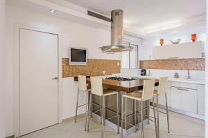 una cocina con armarios blancos y una isla de cocina con taburetes en Duplex Penthouse 3BR Asirey Tsyon By Holiday-rentals, en Tel Aviv