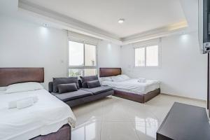 sala de estar con 2 camas y sofá en Duplex Penthouse 3BR Asirey Tsyon By Holiday-rentals, en Tel Aviv