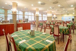 a dining room with tables and chairs with green table cloth at Hungarospa Thermal Hotel in Hajdúszoboszló