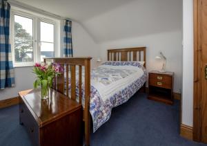 a bedroom with a bed and a vase of flowers on a table at Pelydryn in Abersoch