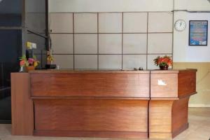 a wooden counter in a room with a clock on the wall at Capital O 91650 Hotel Pratama in Kolaka