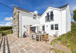 Casa blanca con patio con mesa y sillas en Pentraeth Cottage, en Abersoch