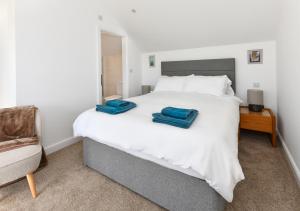 a bedroom with a bed with two blue towels on it at Pentraeth Cottage in Abersoch