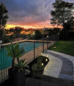 a fence next to a swimming pool with a sunset at Rare Find! 5-Bedroom Home with Pool and Pool Table in Muswellbrook