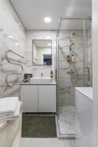 a white bathroom with a sink and a shower at RIVERFRONT 2BD Old Town Apartment by Hostlovers in Kaunas