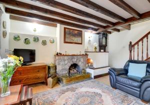 een woonkamer met een open haard, een bank en een tv bij Old Newton Cottage in Porthcawl