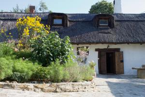 uma casa com telhado de palha e um jardim em Sasfészek Pihenő em Kőszegszerdahely