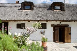 an old house with a thatched roof with a yard at Sasfészek Pihenő in Kőszegszerdahely