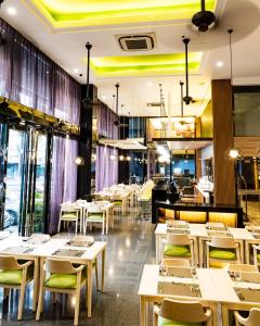 a restaurant with white tables and chairs and windows at Prime Asia Hotel in Angeles